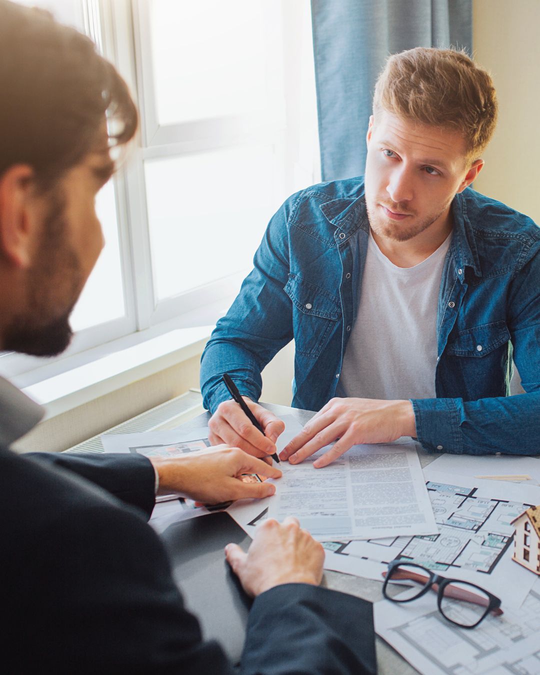 Man signing documents talking to an agent